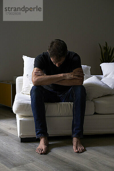Deprimierter Mann sitzt auf Sofa