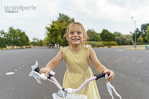 Glückliches Mädchen  das im Park auf dem Fahrrad sitzt