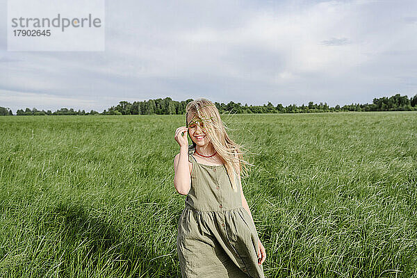 Happy girl holding grass standing in field