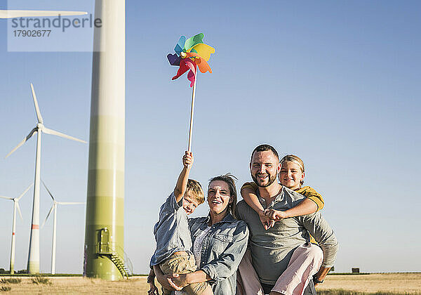 Optimistische Familie steht im Windpark  Sohn trägt buntes Windrad