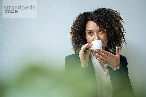 Reife Geschäftsfrau trinkt Kaffee vor der Wand