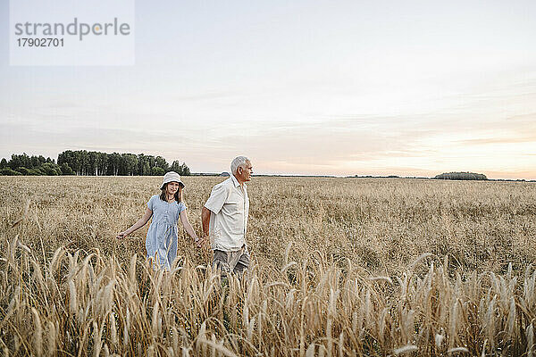 Älterer Bauer mit Mädchen  das im Roggenfeld spaziert