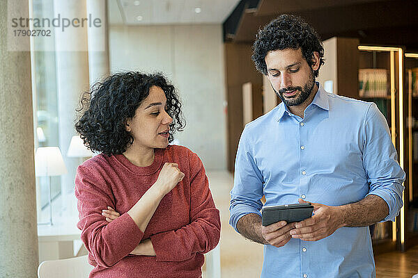 Mann und Frau diskutieren über Tablet-PC in der Bibliothek