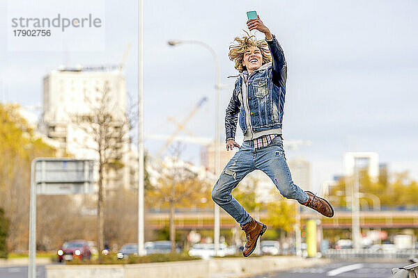 Glücklicher Mann springt und macht ein Selfie mit dem Smartphone