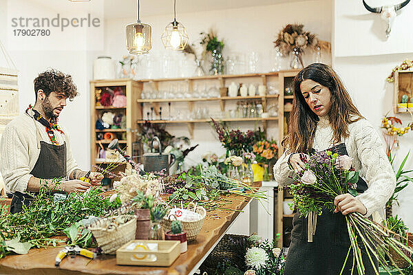 Verkäuferin macht Blumenstrauß von Kollegin im Blumenladen