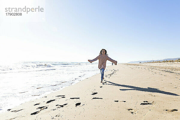 Glückliches Mädchen  das an einem sonnigen Tag am Strand läuft