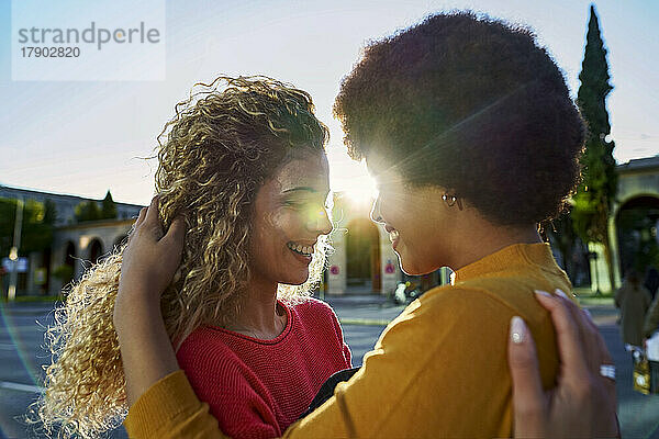 Smiling lesbian couple embracing on sunny day