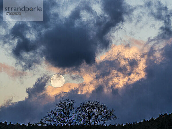 Vollmond geht hinter Gewitterwolken auf