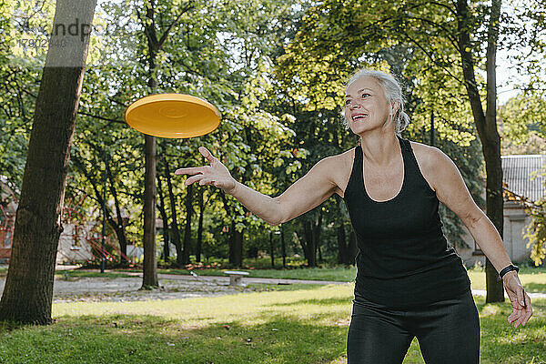 Reife Frau wirft Frisbee im Park