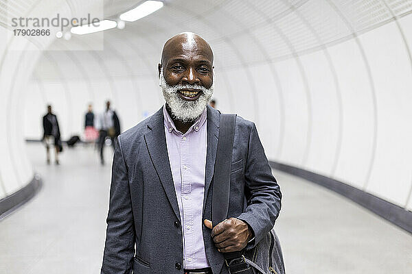Lächelnder älterer Geschäftsmann im U-Bahn-Tunnel