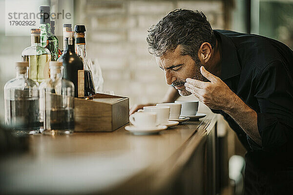 Mann mit geschlossenen Augen riecht Kaffee auf dem Tisch