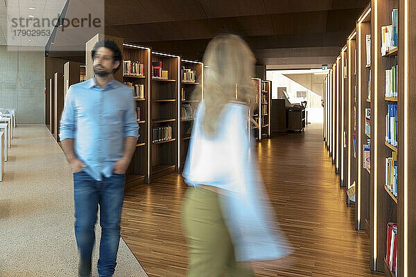 Verschwommene Bewegung von Mann und Frau beim Gehen in der Universitätsbibliothek
