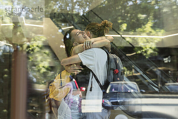 Glückliches Paar  das sich umarmt und durch ein Glasfenster gesehen wird