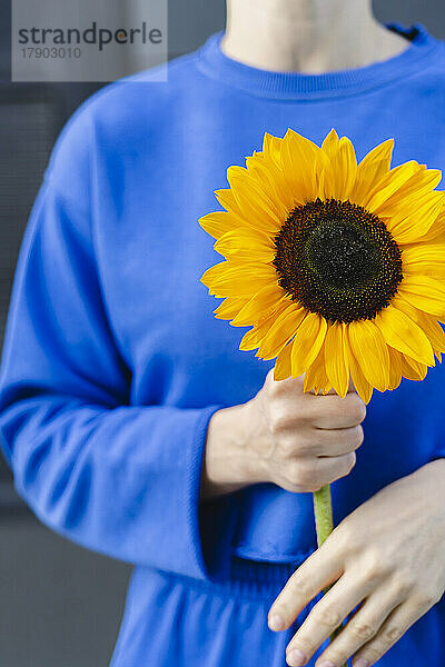 Frau steht und hält Sonnenblume
