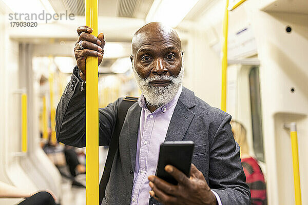Älterer Passagier mit Smartphone in der U-Bahn
