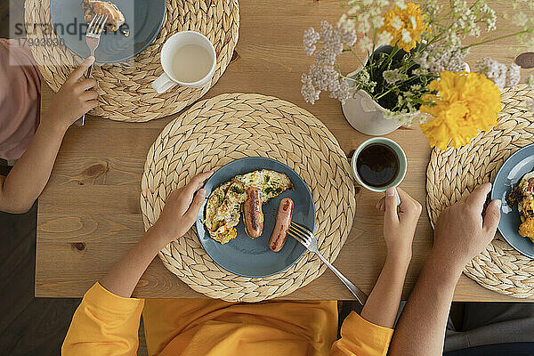 Girl eating breakfast with family at dining table