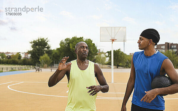 Reifer Mann spricht mit Sohn auf dem Basketballplatz