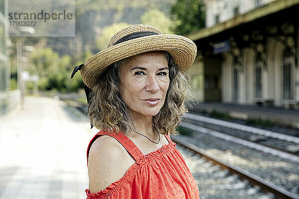 Ältere Frau mit Hut am Bahnhof