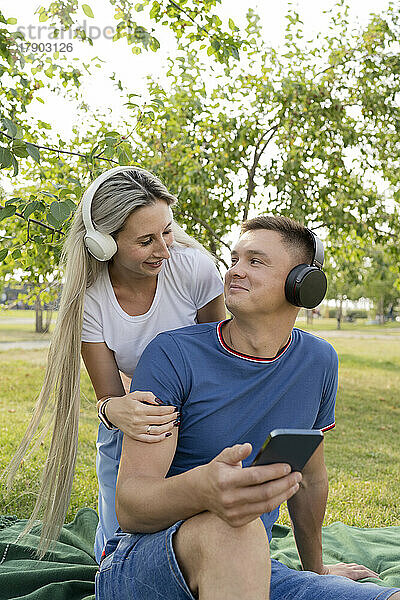 Junges Paar trägt Kopfhörer und hört Musik im Park