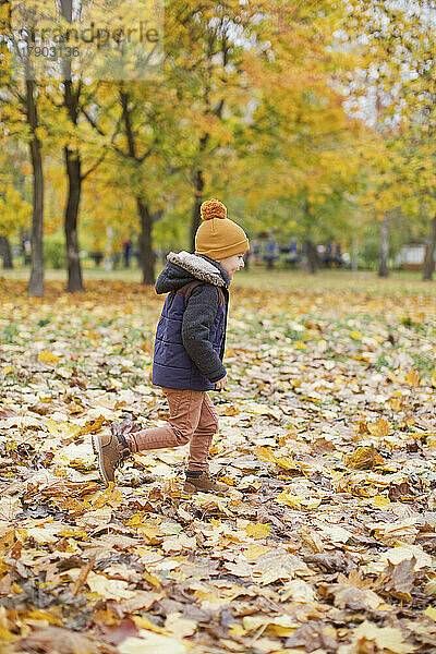 Junge trägt warme Kleidung und spielt im Park