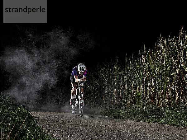 Sportler fährt nachts Fahrrad auf der Straße