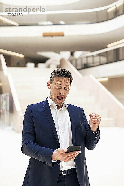 Erfolgreicher Geschäftsmann nutzt Smartphone in der Lobby