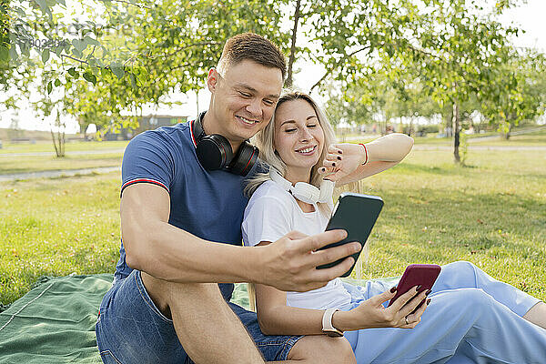 Junge Männer und Frauen unterhalten sich per Videoanruf über ihr Smartphone im Park