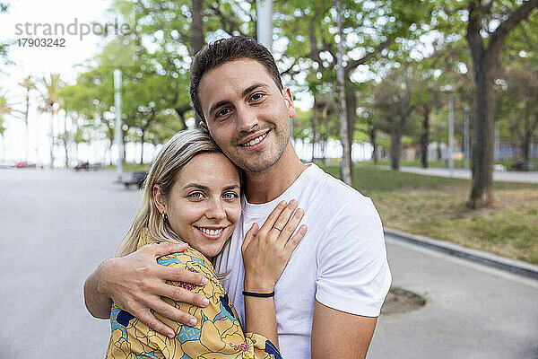 Smiling young couple hugging each other at park