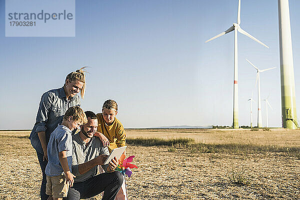 Lächelnde Familie nutzt digitales Tablet im Windpark