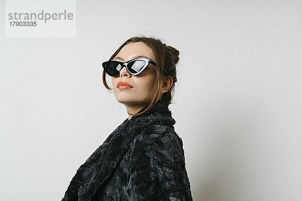 Confident woman wearing sunglasses in studio