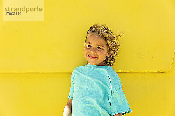 Smiling cute boy standing in front of yellow wall