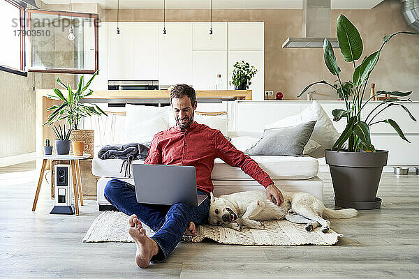 Freiberufler sitzt mit Laptop und streichelt seinen Hund