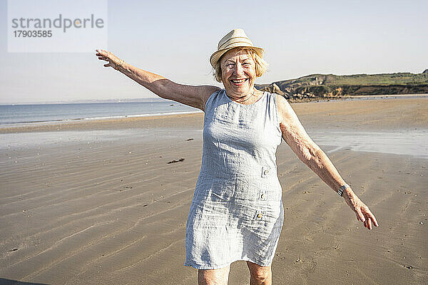 Glückliche Frau mit erhobenen Armen genießt den Urlaub am Strand