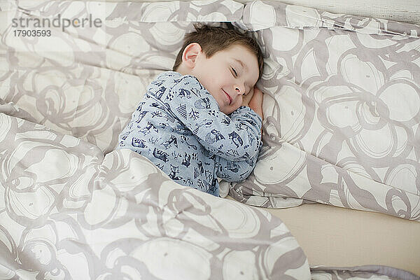 Lächelnder Junge  der auf dem Bett schläft