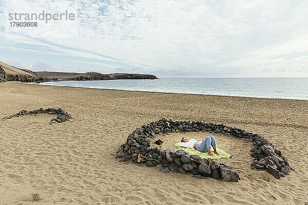Junge Frau liegt inmitten von Felsen am Strand