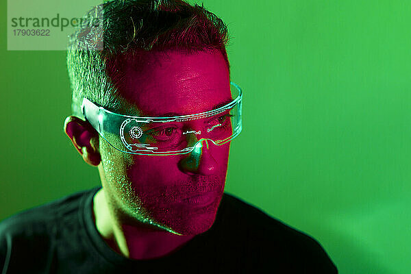 Nachdenklicher Mann mit Smart-Brille vor grünem Hintergrund