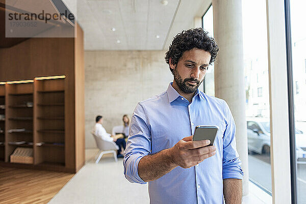 Professor nutzt Smartphone in der Bibliothek