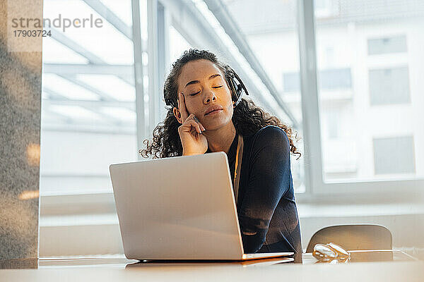 Kundendienstmitarbeiter mit geschlossenen Augen entspannt sich am Schreibtisch im Büro