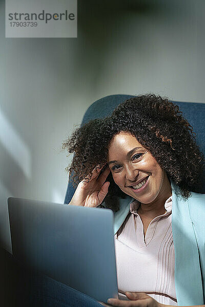 Glückliche Geschäftsfrau mit Laptop im Büro