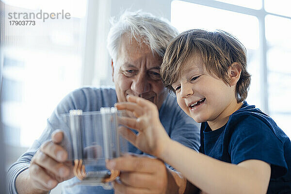 Lächelnder Enkel und Großvater untersuchen das Heizmodul zu Hause
