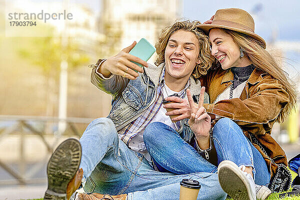 Mann zeigt Friedenszeichen und macht ein Selfie mit einem Freund per Smartphone