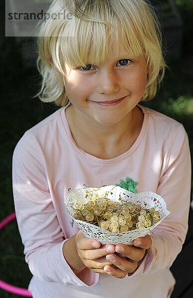 Porträt eines kleinen Mädchens mit frisch gepflückten Johannisbeeren