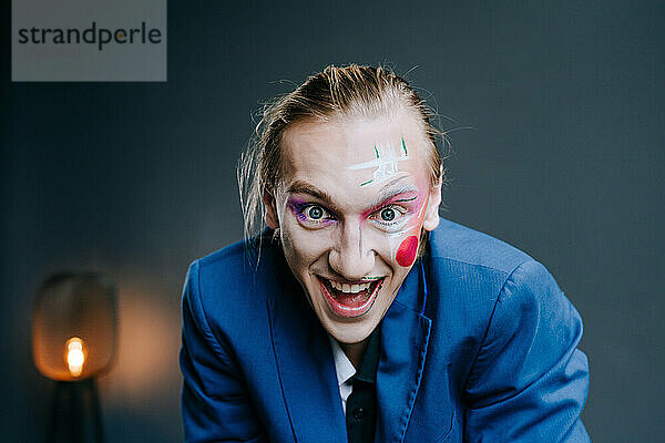 Fröhlicher junger Mann mit Clown-Make-up im Gesicht