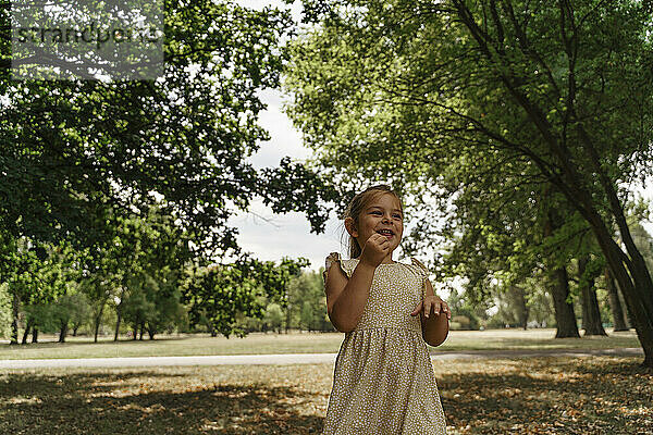Glückliches Mädchen  das inmitten von Bäumen im Park steht