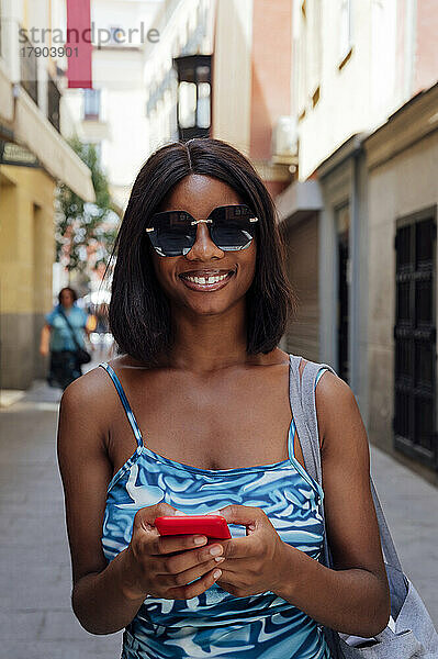 Glückliche Frau mit Sonnenbrille und Mobiltelefon