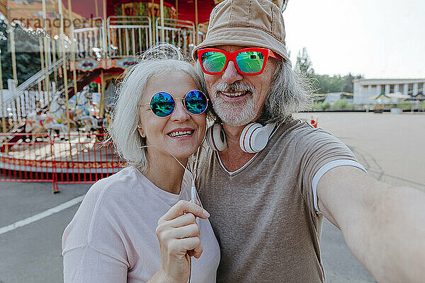 Glückliches Paar mit Sonnenbrille macht Selfie im Vergnügungspark