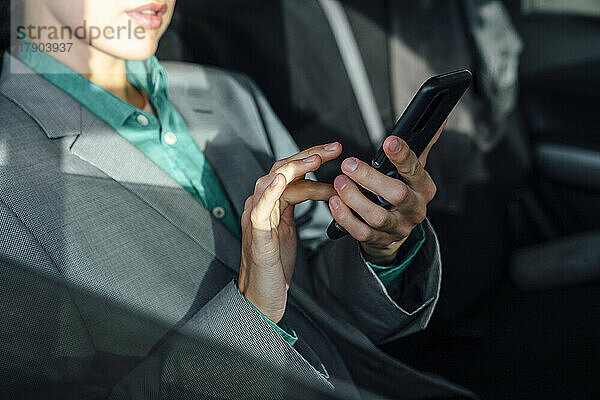 Geschäftsfrau benutzt Mobiltelefon im Auto