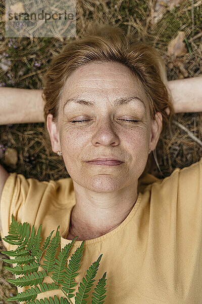 Reife Frau mit geschlossenen Augen entspannt sich im Wald