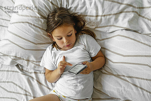 Mädchen benutzt Smartphone zu Hause im Bett