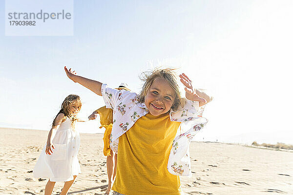 Fröhlicher Junge  der an einem sonnigen Tag mit der Familie am Strand genießt